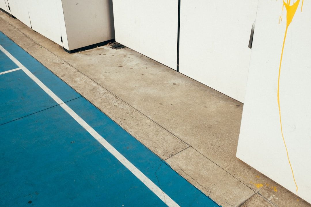Blått sportgolv intill en betongyta och vita väggpaneler.