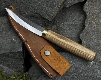 Täljkniv med trähandtag och läderslida på mörk skiffer